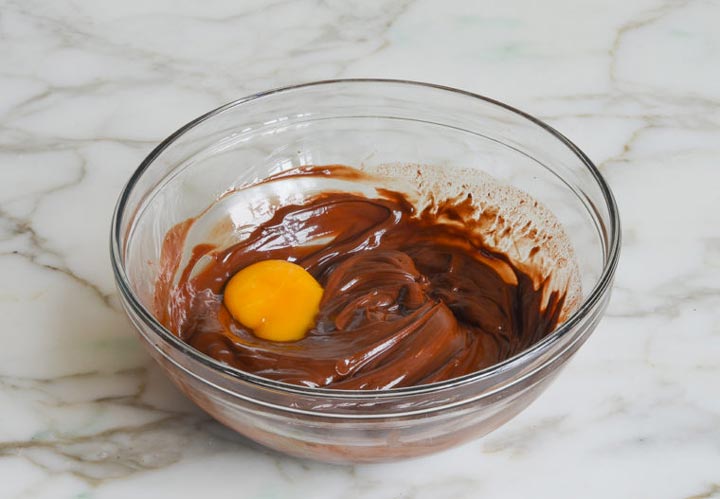 طرز تهیه موس شکلاتی - در مرحله دوم زرده تخم مرغ را یکی یکی اضافه بکنید و هم بزنید.